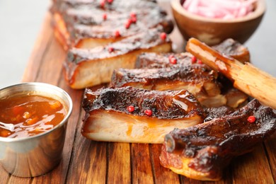 Photo of Delicious pork ribs, sauce and brush on grey table, closeup