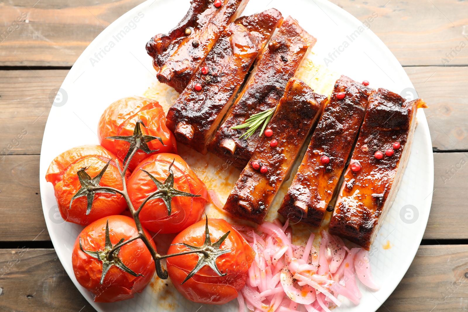Delicious pork ribs, sun dried tomatoes and onion on wooden table, top view Photo of Delicious pork ribs, sun dried tomatoes and onion on wooden table, top view