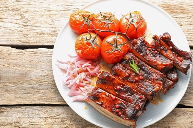 Photo of Delicious pork ribs, sun dried tomatoes and onion on wooden table, top view. Space for text