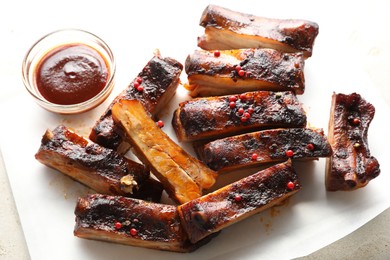 Photo of Delicious pork ribs and sauce on grey table, above view