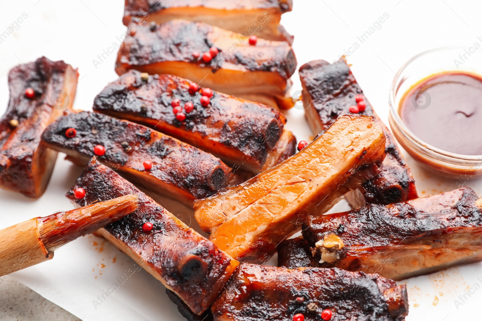 Delicious pork ribs, sauce and brush on table, closeup Photo of Delicious pork ribs, sauce and brush on table, closeup