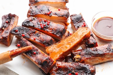 Photo of Delicious pork ribs, sauce and brush on table, closeup