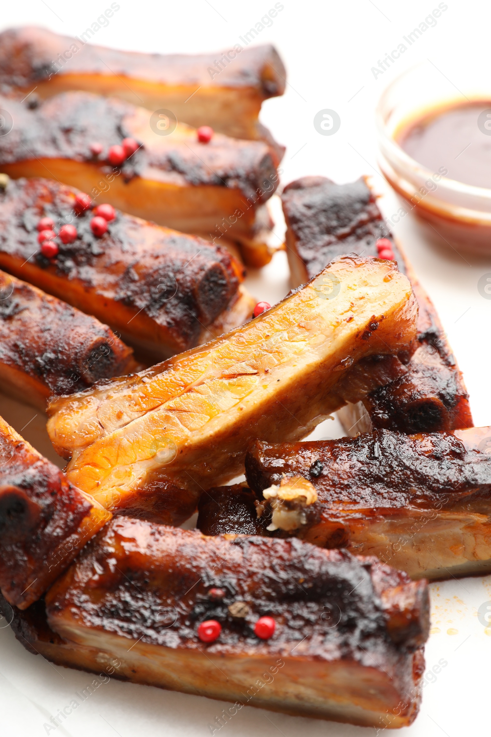 Delicious pork ribs and sauce on parchment paper, closeup Photo of Delicious pork ribs and sauce on parchment paper, closeup