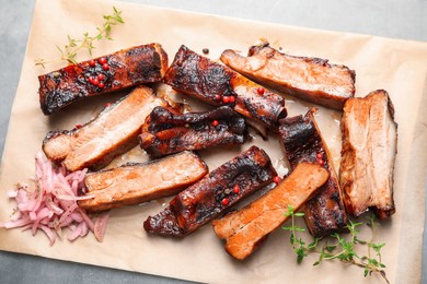 Photo of Delicious pork ribs, thyme and onion on grey table, top view