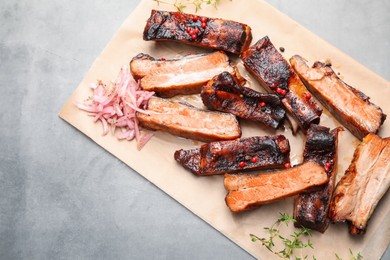 Photo of Delicious pork ribs, thyme and onion on grey textured table, top view. Space for text