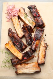 Photo of Delicious pork ribs, thyme and onion on grey table, top view