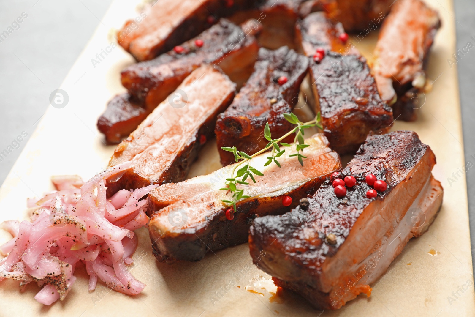 Delicious pork ribs, thyme and onion on grey table, closeup Photo of Delicious pork ribs, thyme and onion on grey table, closeup