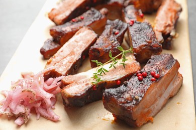 Photo of Delicious pork ribs, thyme and onion on grey table, closeup