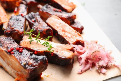 Photo of Delicious pork ribs, thyme and onion on grey table, closeup