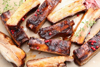 Photo of Delicious pork ribs and thyme on parchment paper, top view