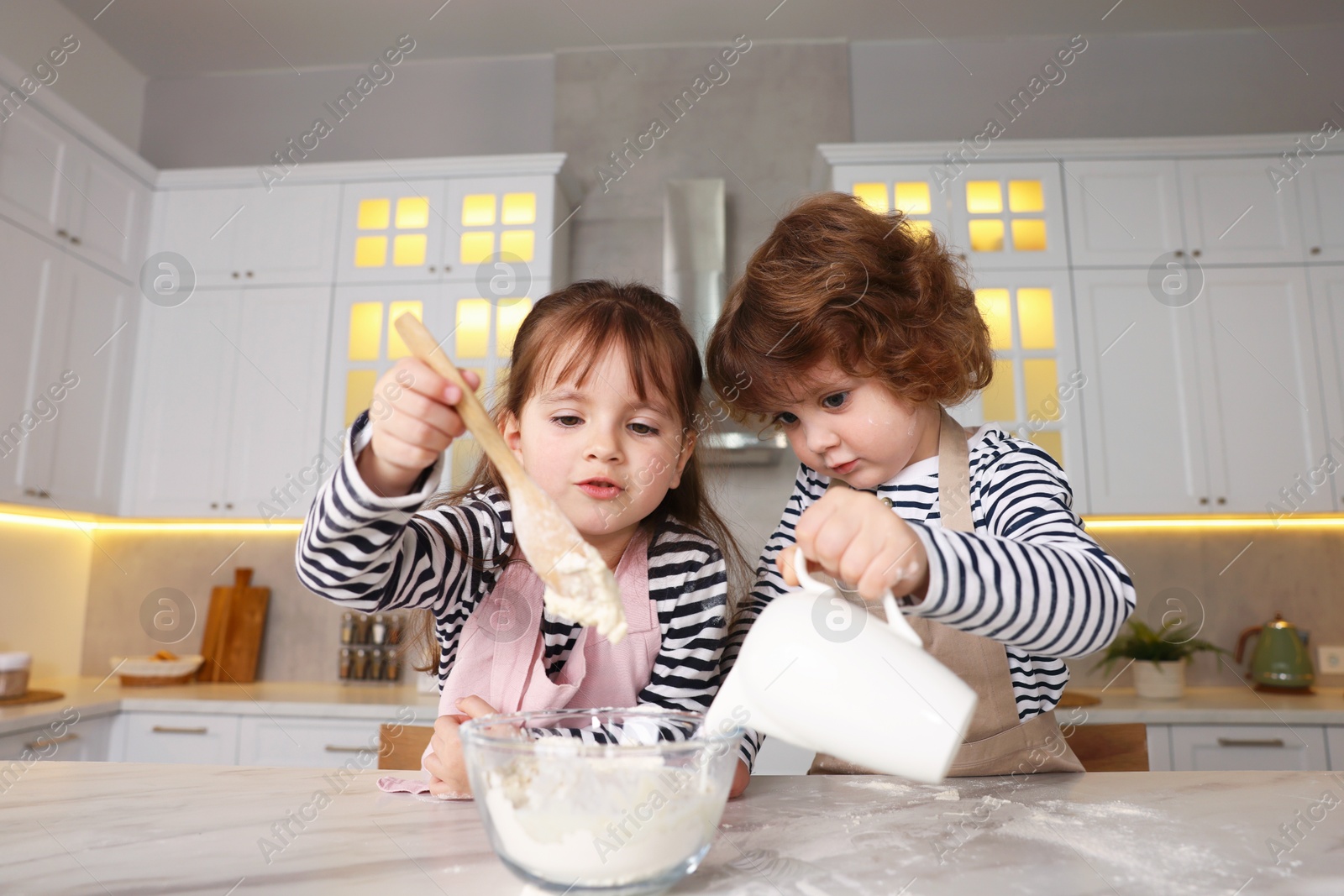 Cooking recipe. Cute children making dough for cookies at table in kitchen, low angle view Photo of Cooking recipe. Cute children making dough for cookies at table in kitchen, low angle view