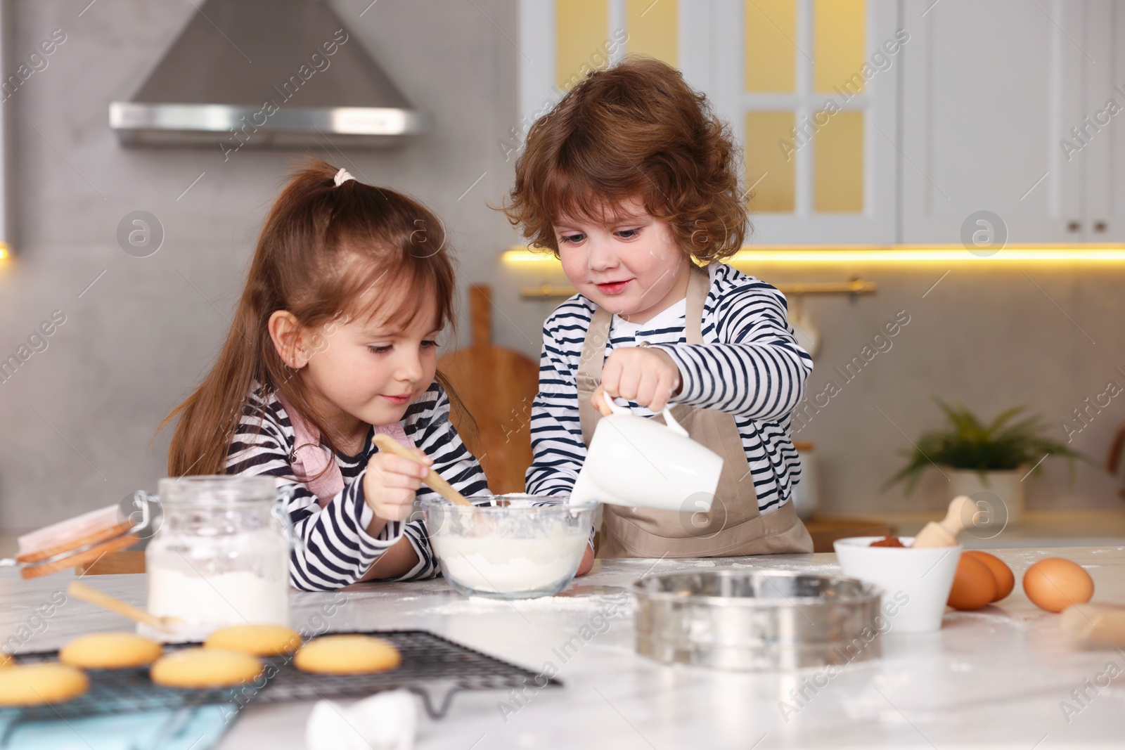 Cooking recipe. Cute children making dough for cookies at table in kitchen Photo of Cooking recipe. Cute children making dough for cookies at table in kitchen