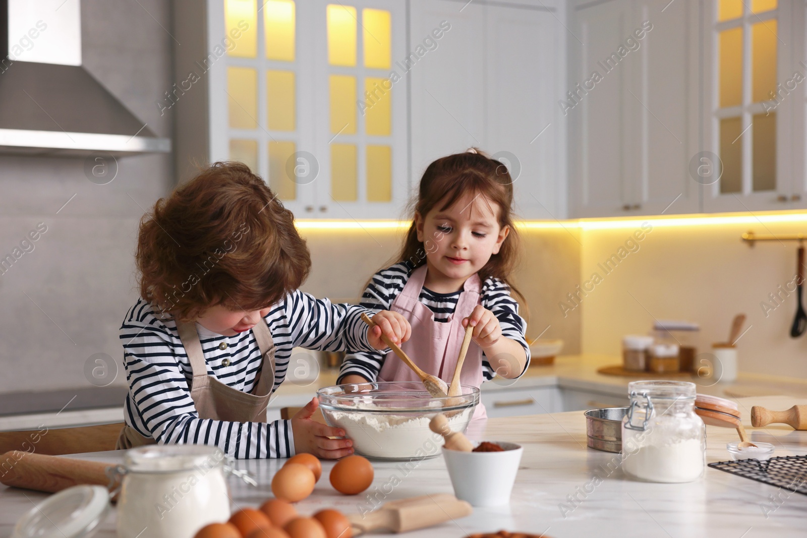 Cooking recipe. Cute children making dough for cookies at table in kitchen Photo of Cooking recipe. Cute children making dough for cookies at table in kitchen