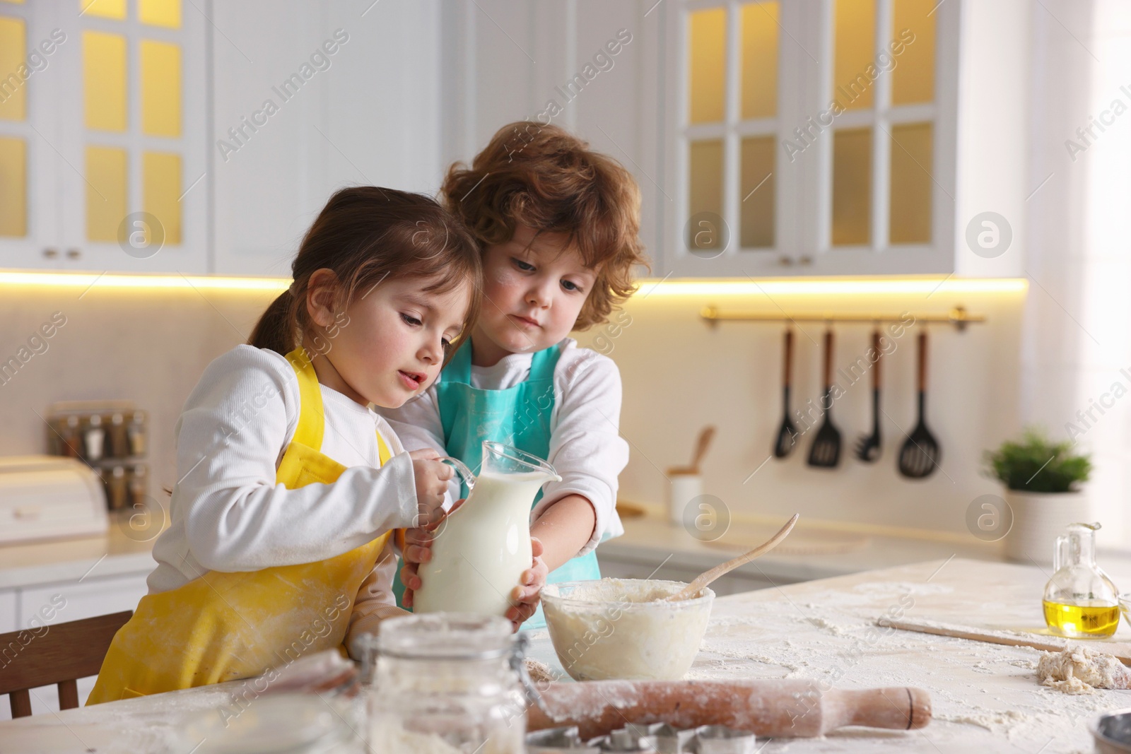 Cooking recipe. Cute children making dough for cookies at table in kitchen Photo of Cooking recipe. Cute children making dough for cookies at table in kitchen