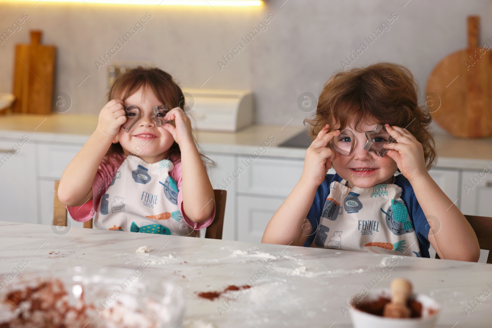 Cooking recipe. Little children with cookie cutters at table in kitchen Photo of Cooking recipe. Little children with cookie cutters at table in kitchen