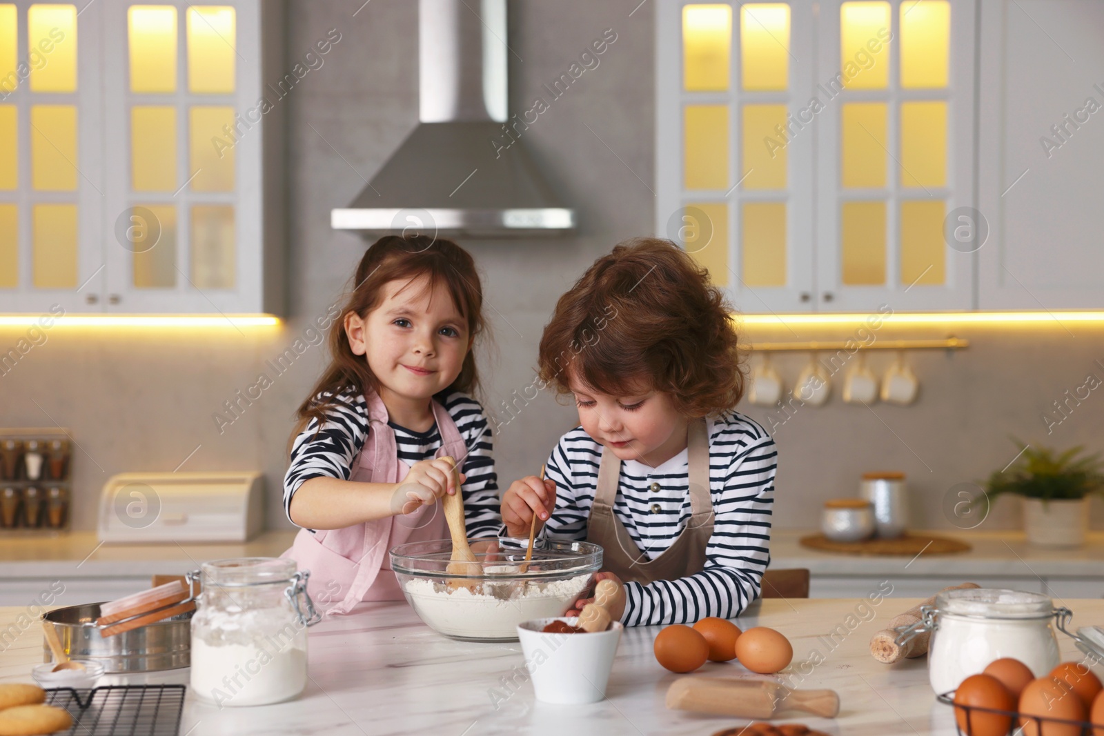 Cooking recipe. Cute children making dough for cookies at table in kitchen Photo of Cooking recipe. Cute children making dough for cookies at table in kitchen