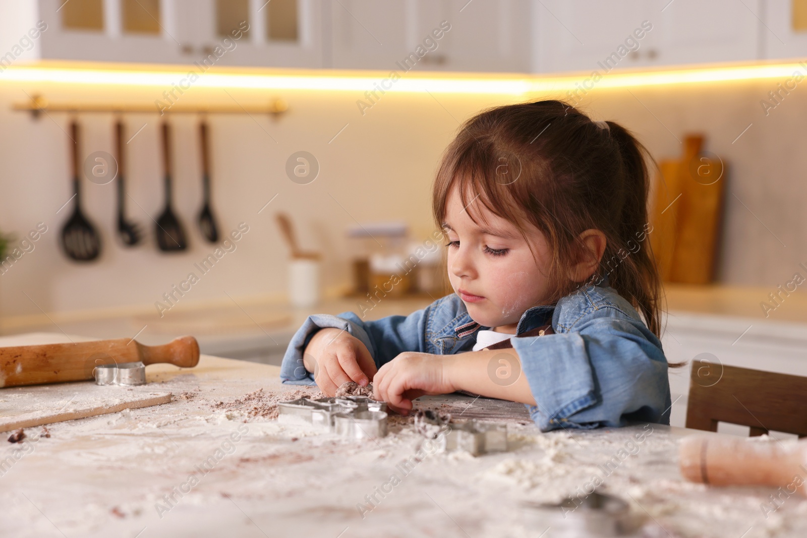 Cooking recipe. Little girl cutting cookie dough with cutters at table indoors. Space for text Photo of Cooking recipe. Little girl cutting cookie dough with cutters at table indoors. Space for text