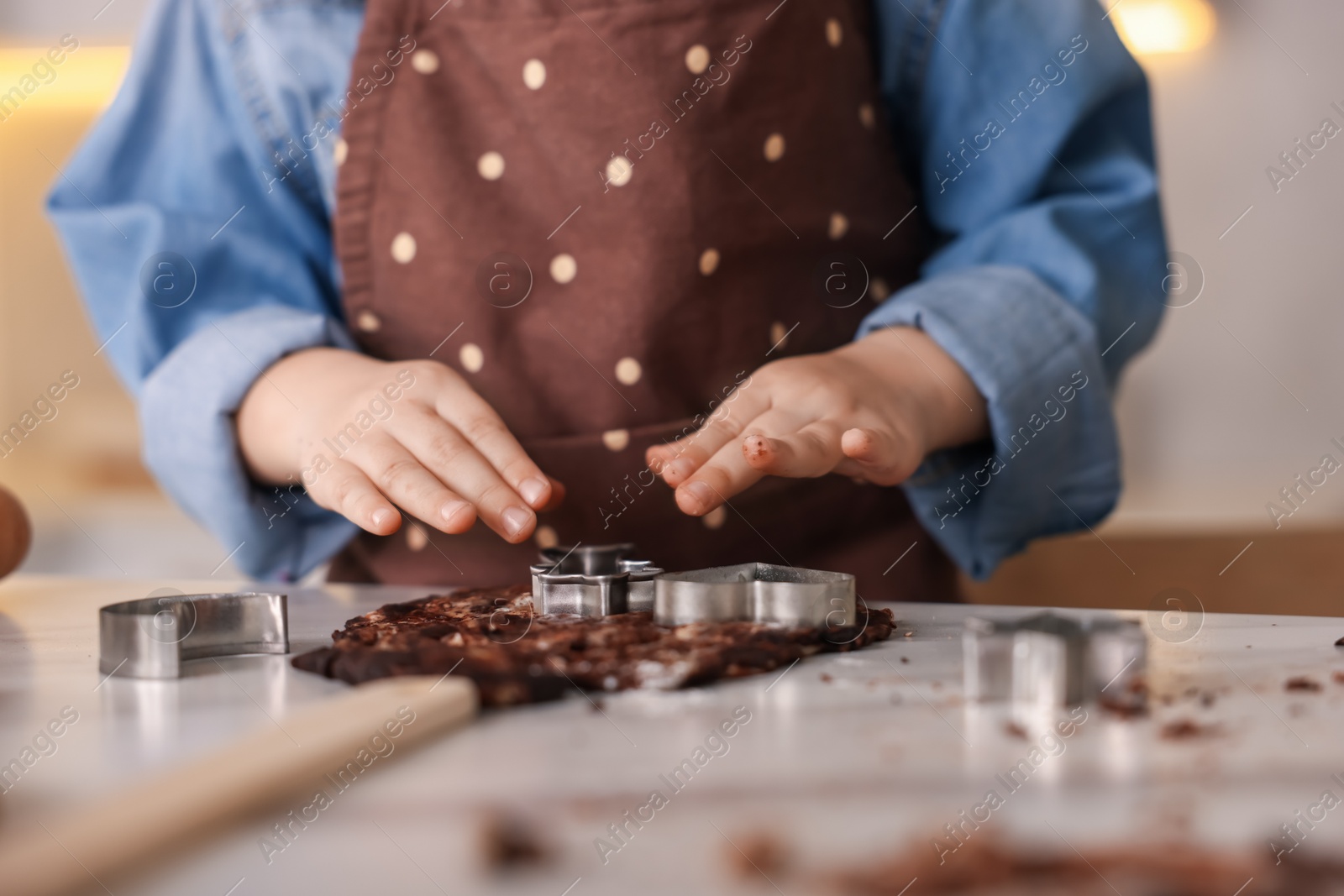Cooking recipe. Little girl cutting cookies with cutters at table in kitchen, closeup Photo of Cooking recipe. Little girl cutting cookies with cutters at table in kitchen, closeup