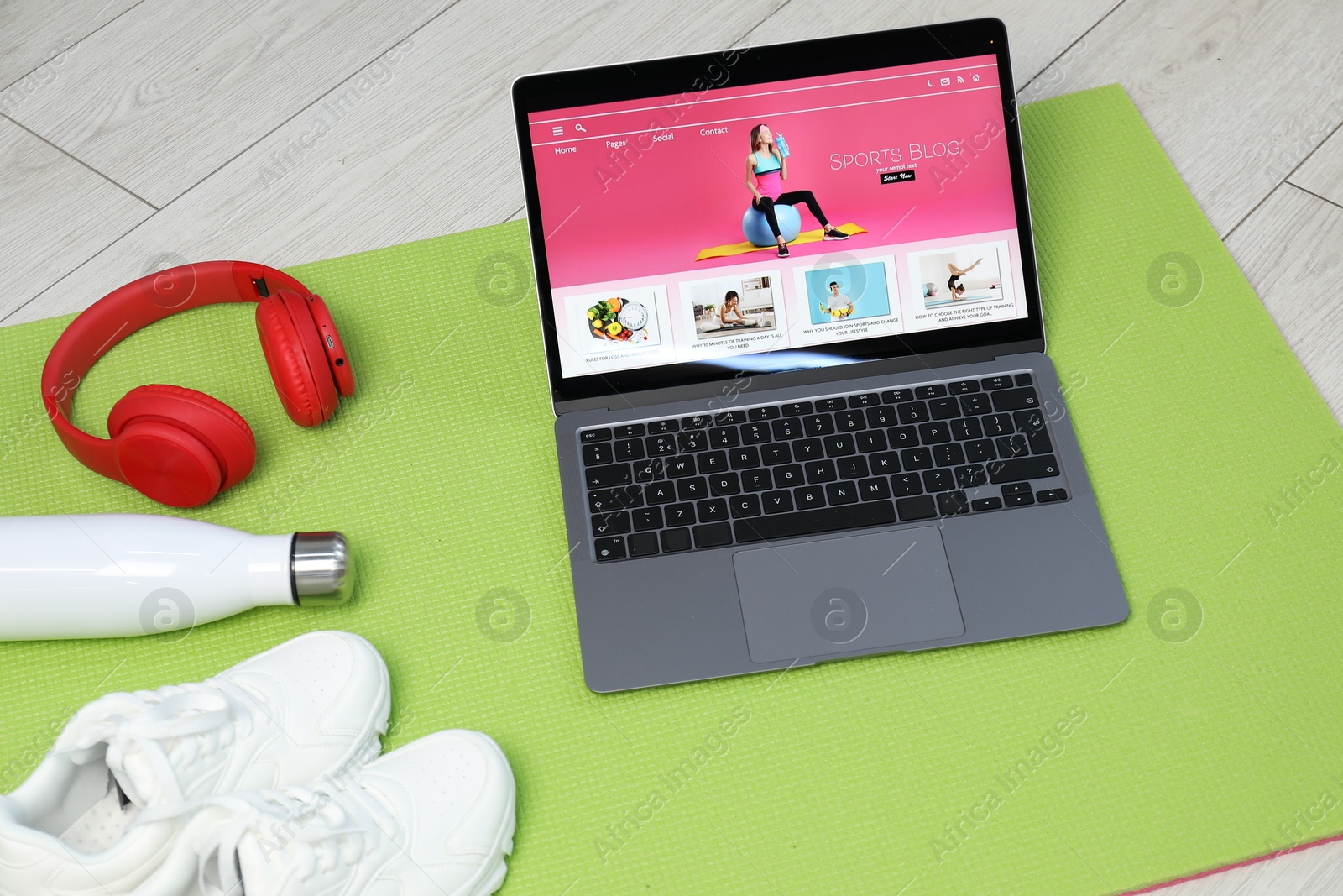 Laptop with sport blog web site and different gym stuff on floor, above view Photo of Laptop with sport blog web site and different gym stuff on floor, above view