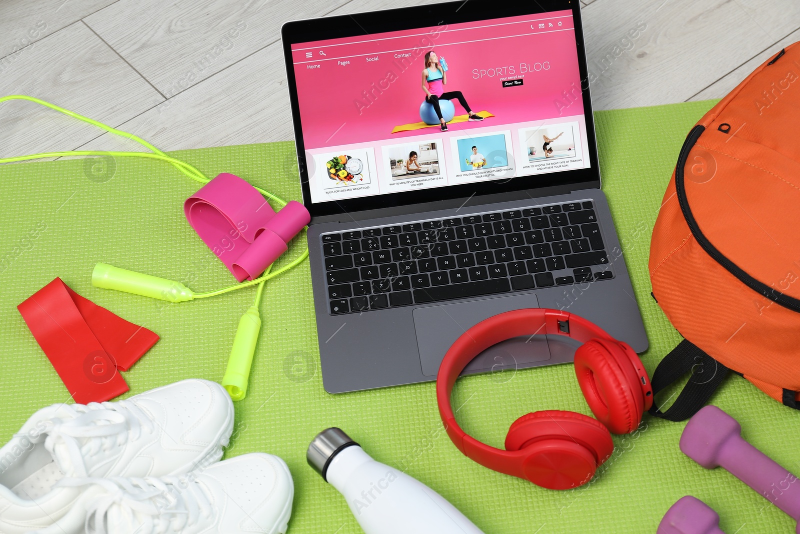 Laptop with sport blog web site and different gym stuff on floor, above view Photo of Laptop with sport blog web site and different gym stuff on floor, above view