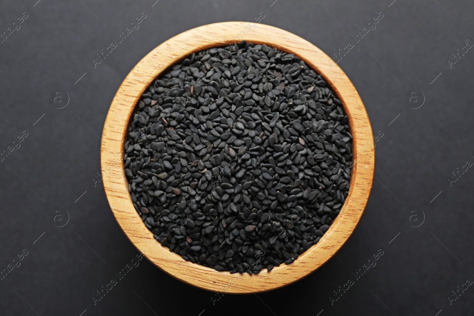 Aromatic black caraway in bowl on dark table, top view Photo of Aromatic black caraway in bowl on dark table, top view