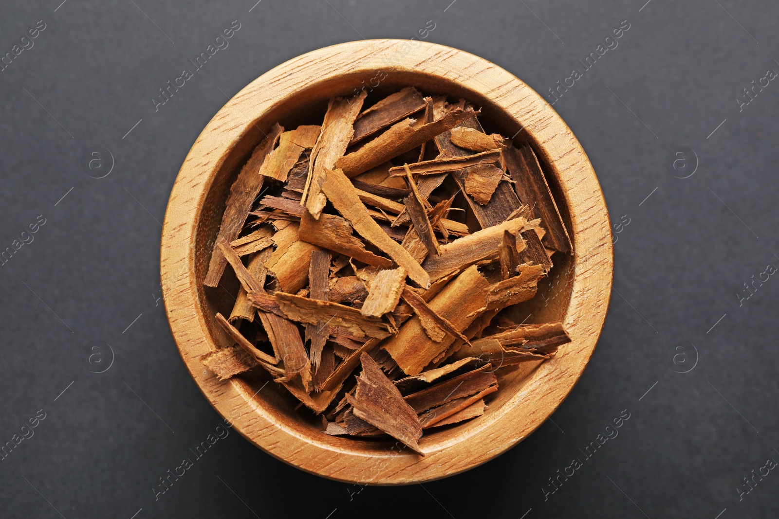 Aromatic cinnamon in bowl on dark table, top view Photo of Aromatic cinnamon in bowl on dark table, top view