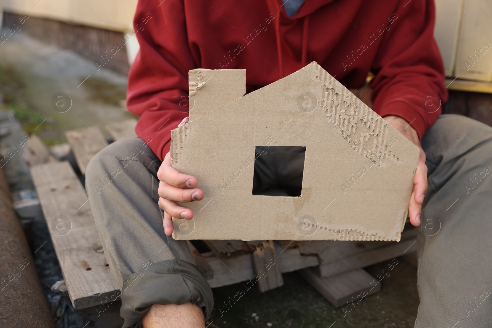 Photo of Homeless man with carton house figure outdoors, closeup