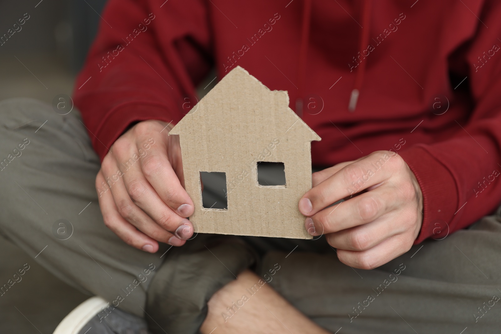 Photo of Homeless man with carton house figure outdoors, closeup