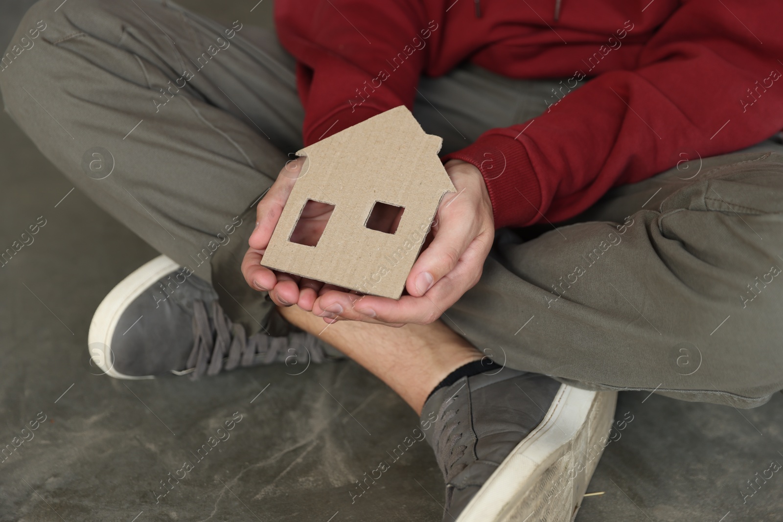 Photo of Homeless man with carton house figure outdoors, closeup