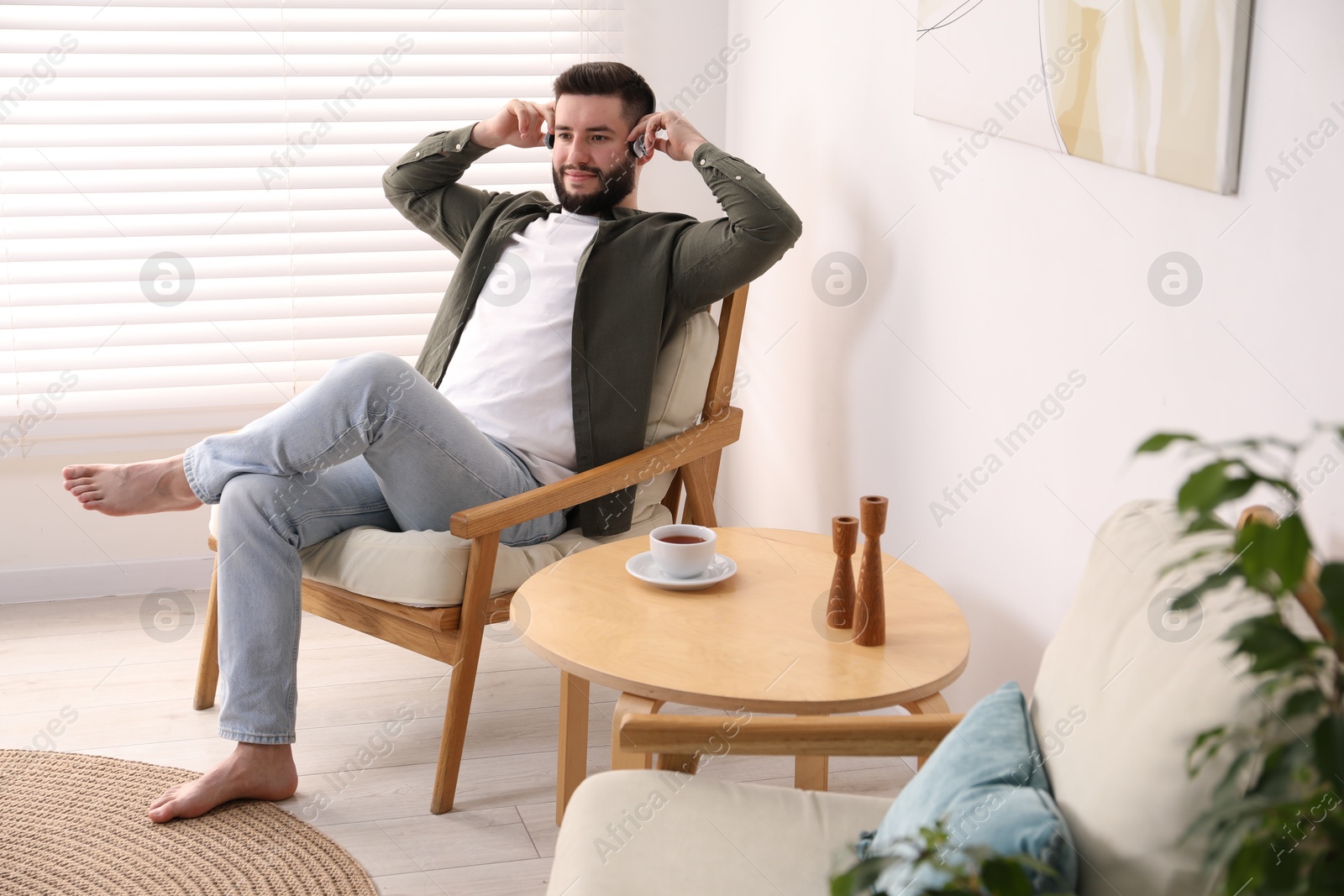 Handsome man with headphones relaxing on armchair at home Photo of Handsome man with headphones relaxing on armchair at home