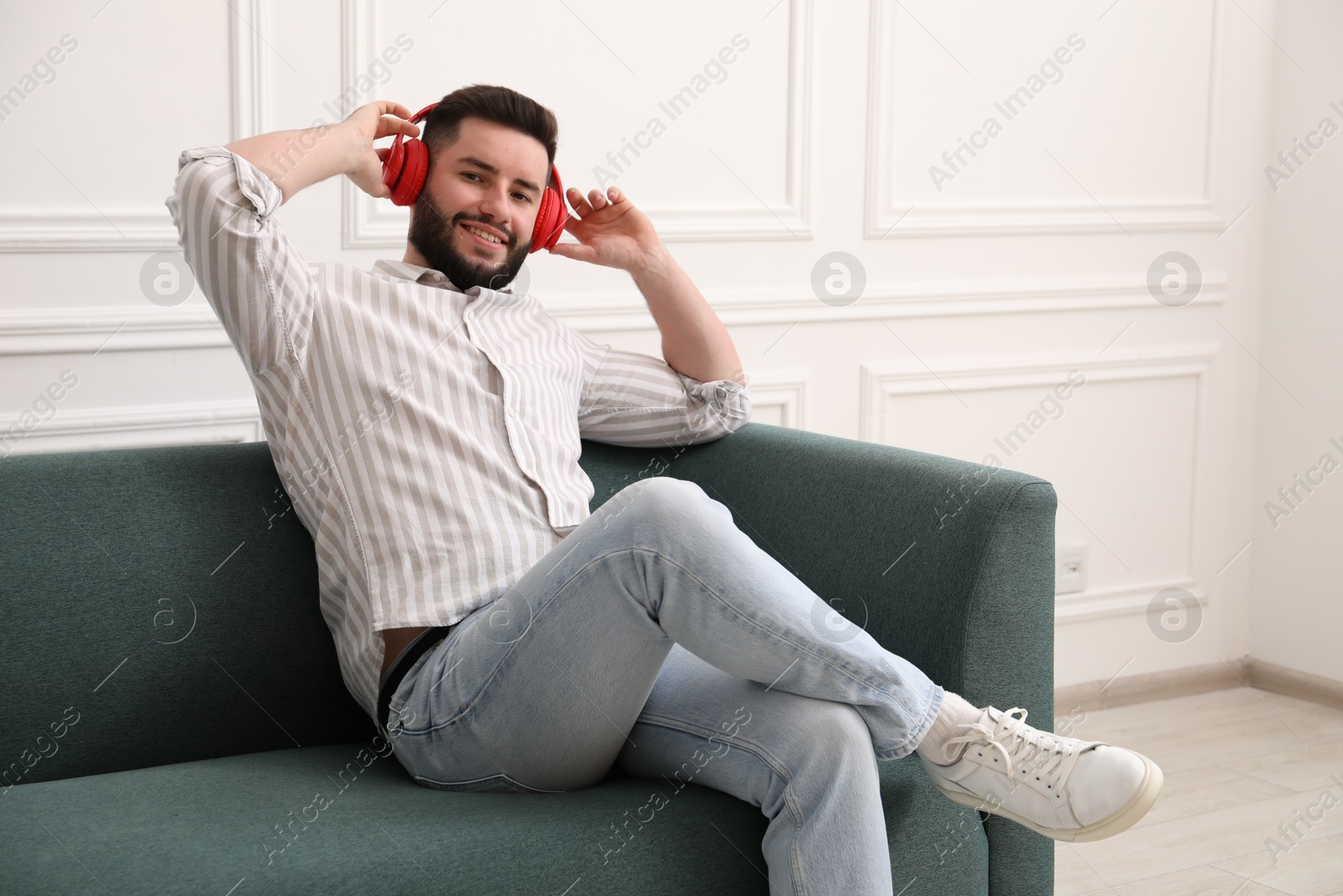 Smiling man in headphones relaxing on sofa at home Photo of Smiling man in headphones relaxing on sofa at home