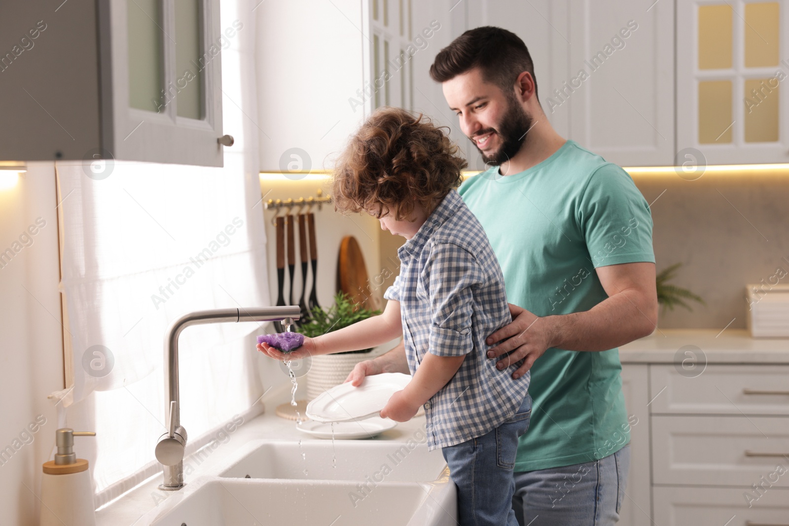 Father and his son washing dishes together in kitchen at home Photo of Father and his son washing dishes together in kitchen at home