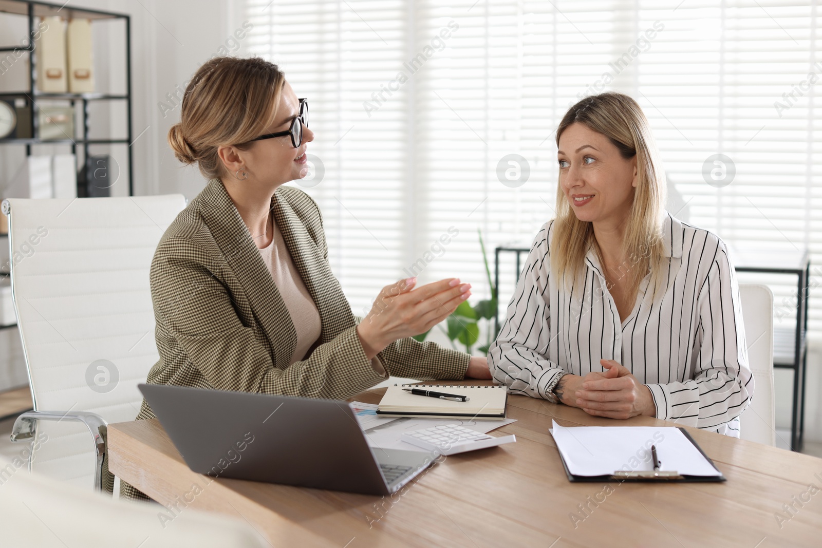 Woman having meeting with banker at desk in office Photo of Woman having meeting with banker at desk in office