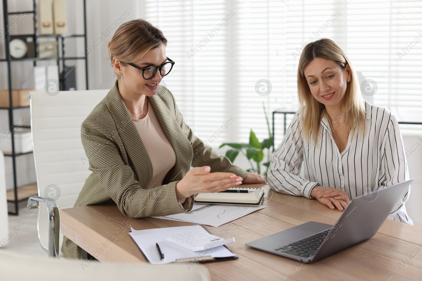 Woman having meeting with banker at desk in office Photo of Woman having meeting with banker at desk in office