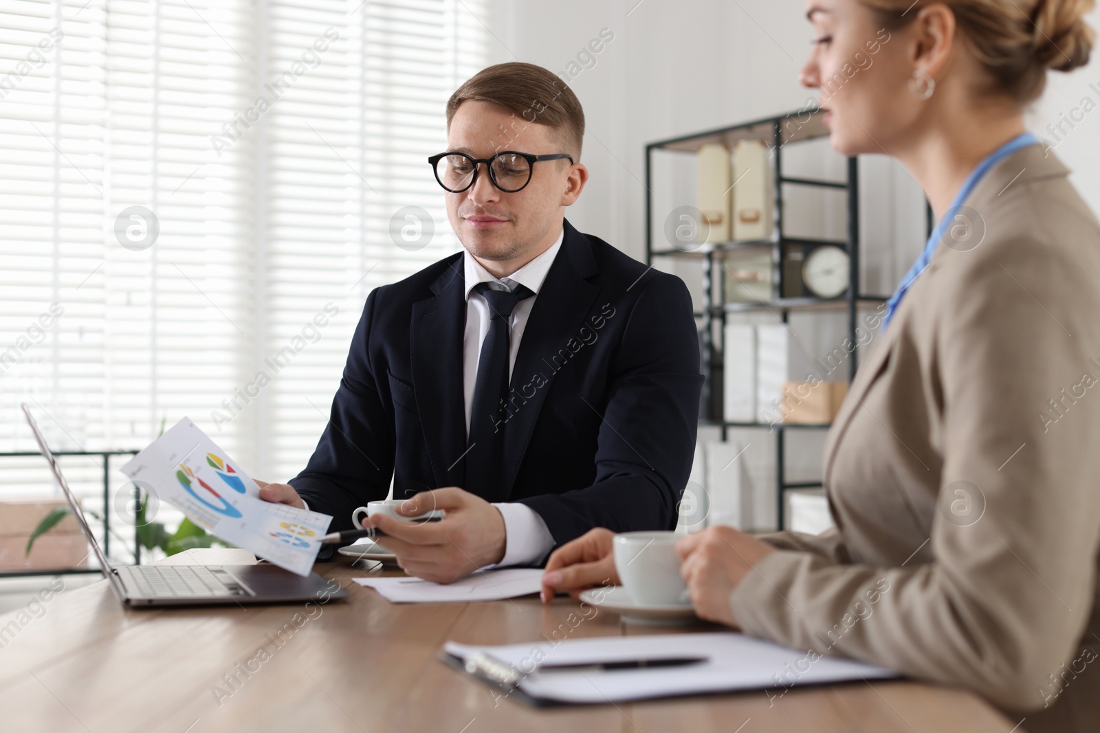 Woman having meeting with banker at desk in office Photo of Woman having meeting with banker at desk in office