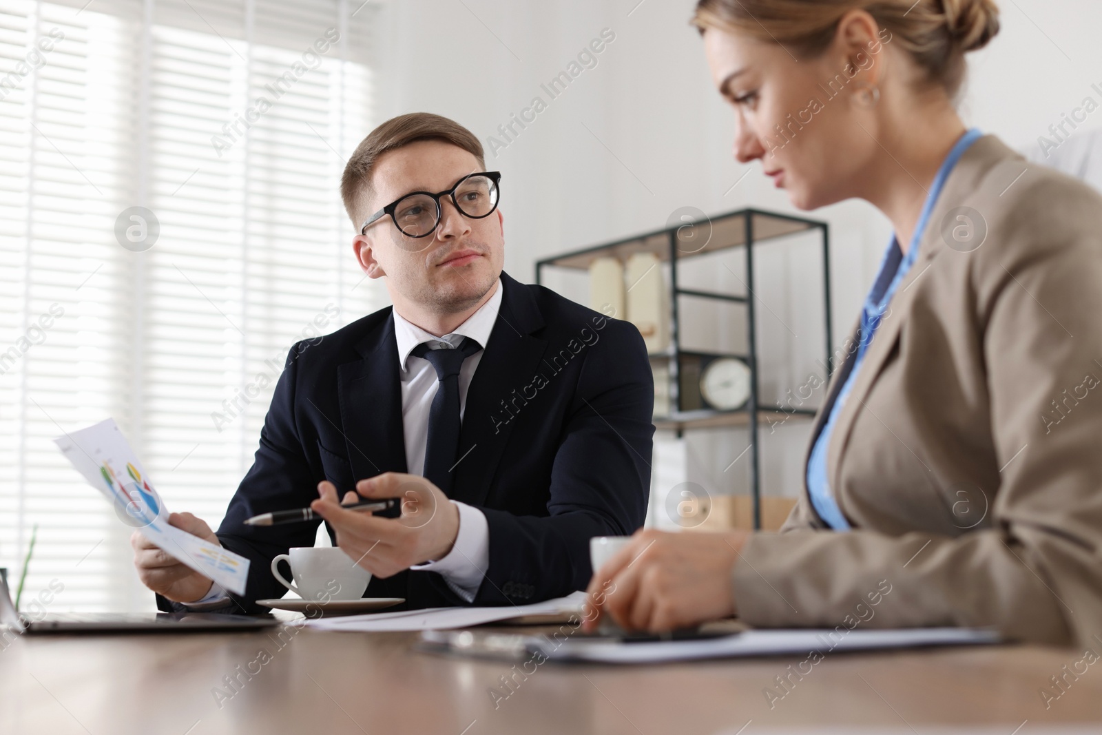 Woman having meeting with banker at desk in office Photo of Woman having meeting with banker at desk in office