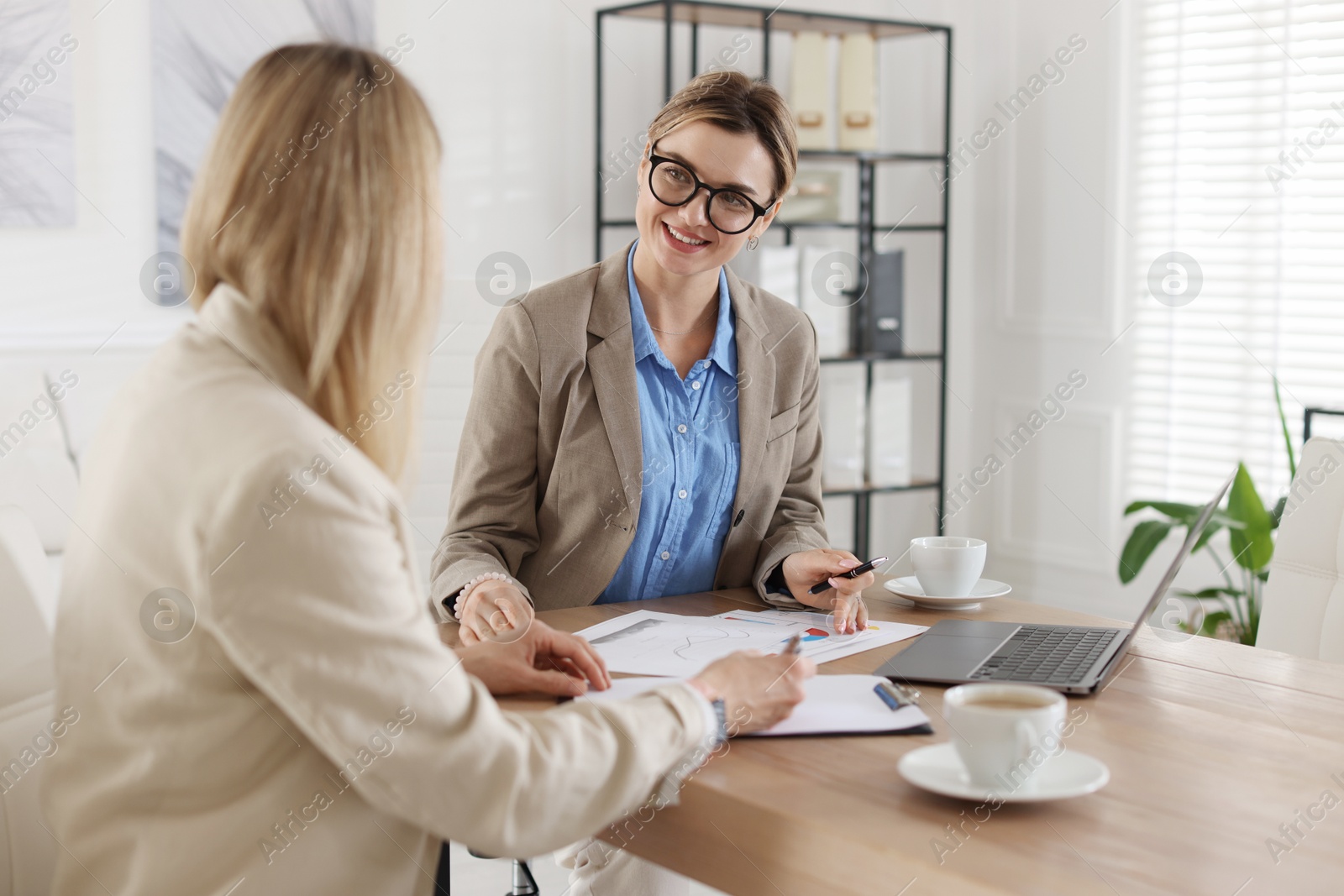 Woman having meeting with banker at desk in office Photo of Woman having meeting with banker at desk in office