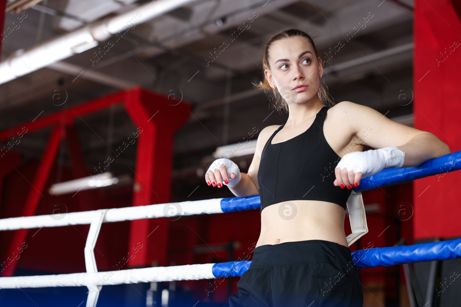 Woman with protective gloves on boxing ring, low angle view. Space for text Photo of Woman with protective gloves on boxing ring, low angle view. Space for text