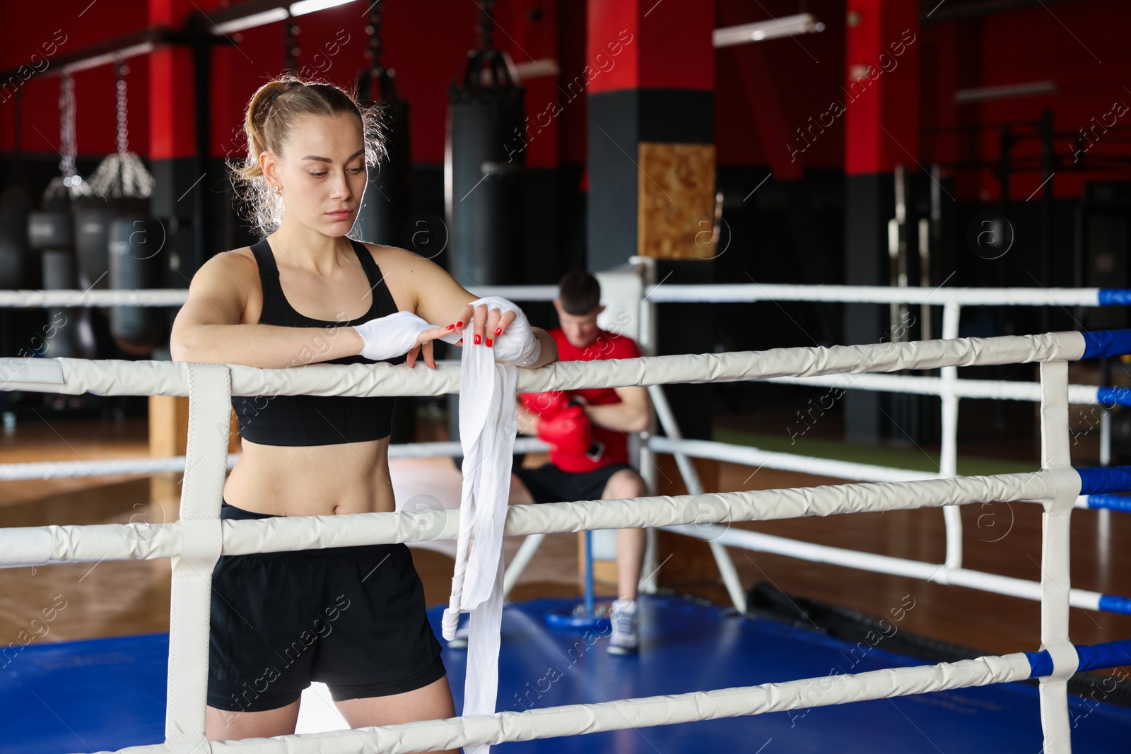 Woman wrapping her hands on boxing ring. Space for text Photo of Woman wrapping her hands on boxing ring. Space for text