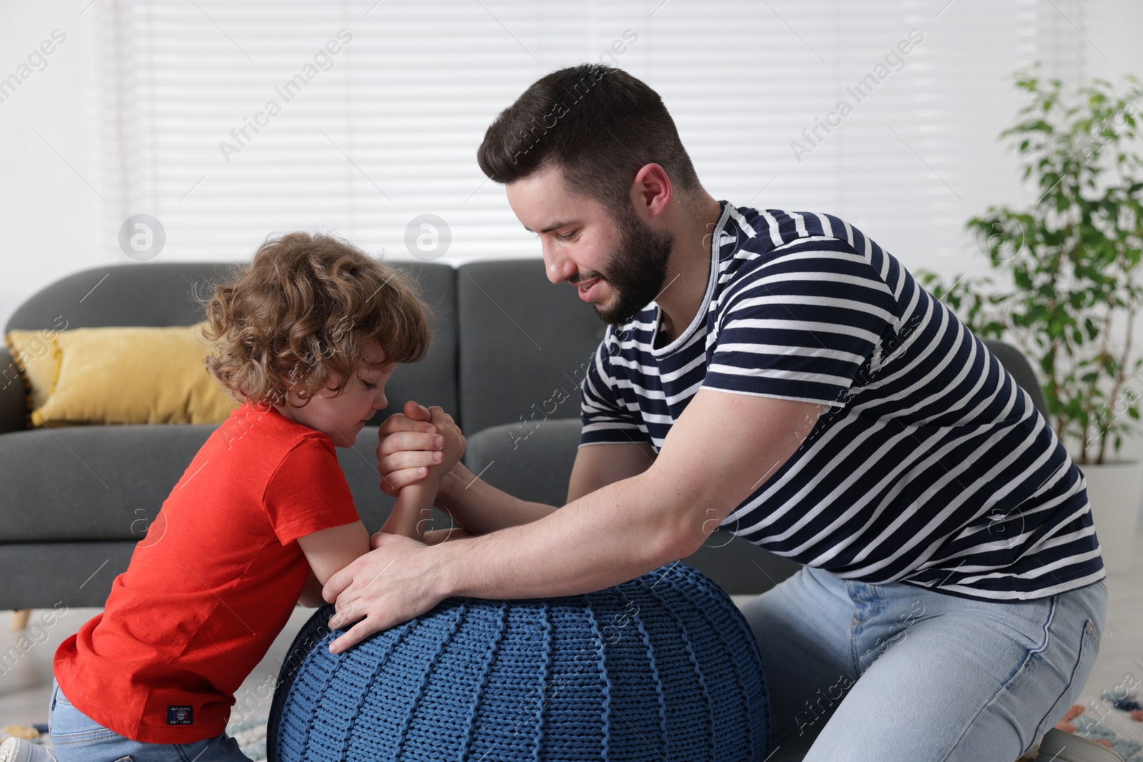 Happy father with his son arm wrestling and spending time together at home Photo of Happy father with his son arm wrestling and spending time together at home