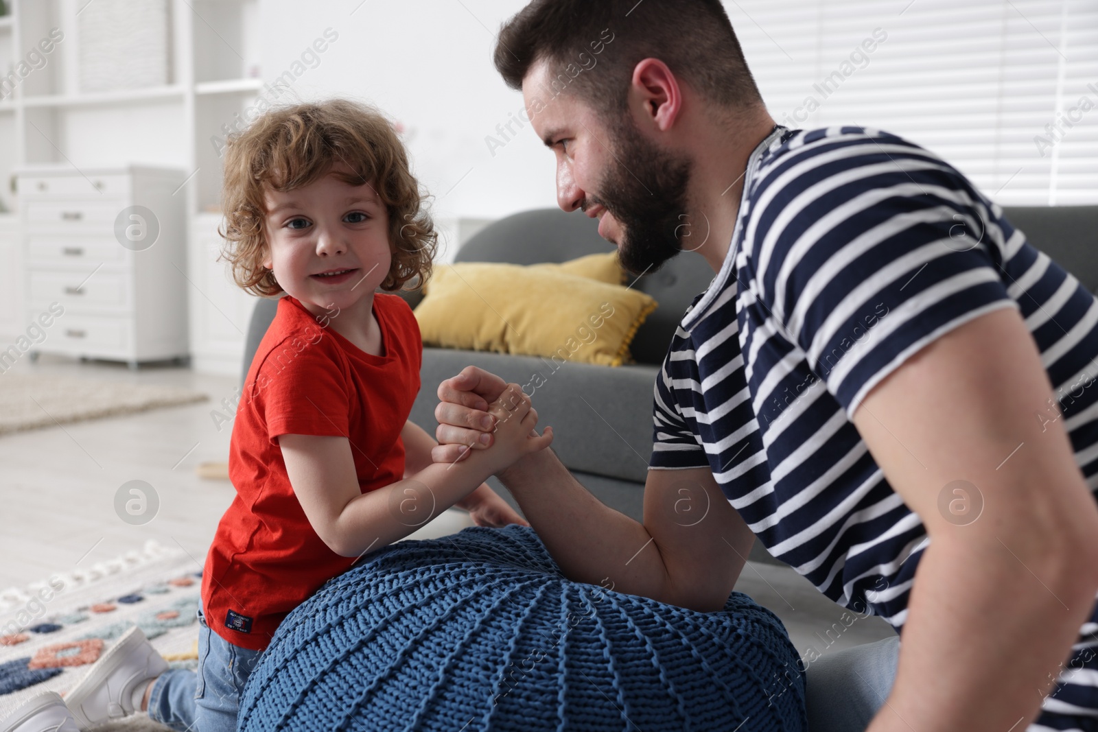 Happy father with his son arm wrestling and spending time together at home Photo of Happy father with his son arm wrestling and spending time together at home