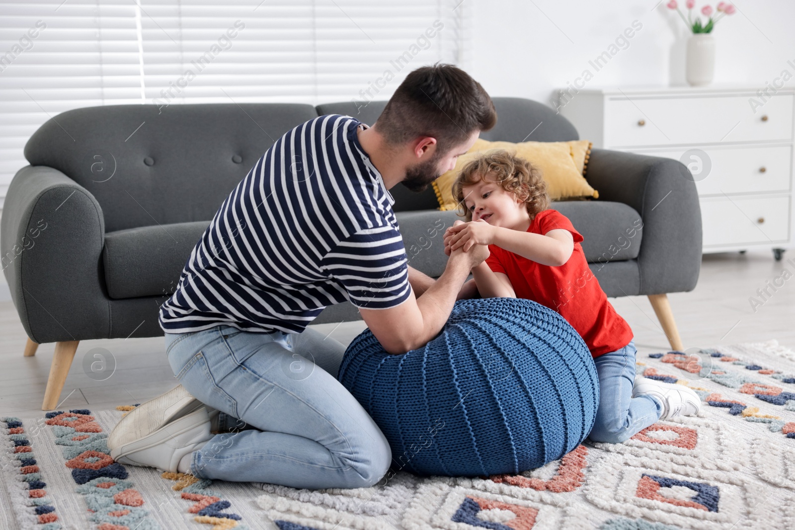 Happy father with his son arm wrestling and spending time together at home Photo of Happy father with his son arm wrestling and spending time together at home