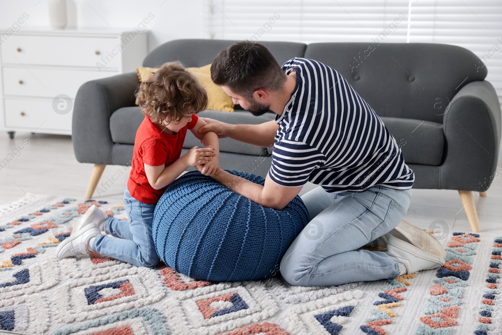 Happy father with his son arm wrestling and spending time together at home Photo of Happy father with his son arm wrestling and spending time together at home