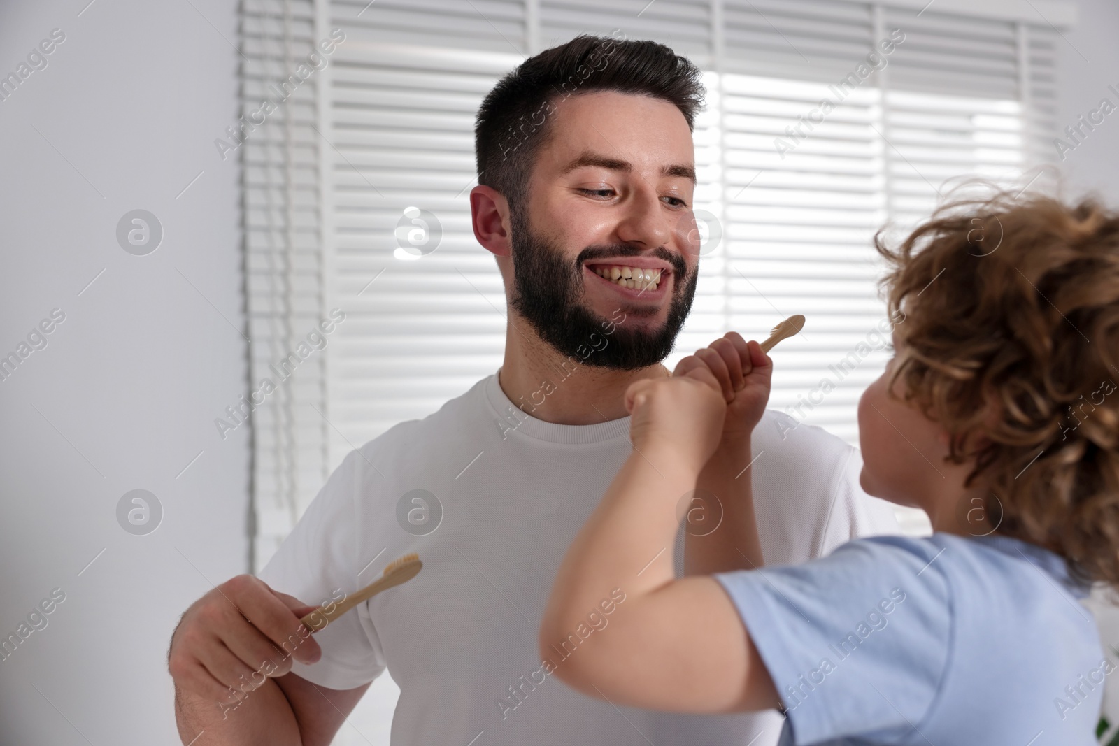 Happy father and his son brushing teeth with toothbrushes in bathroom Photo of Happy father and his son brushing teeth with toothbrushes in bathroom