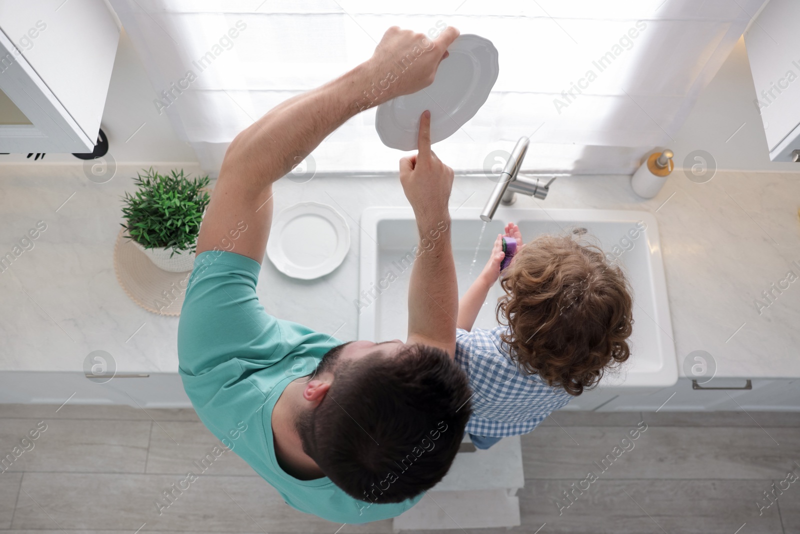 Father and his son washing dishes together in kitchen at home, top view Photo of Father and his son washing dishes together in kitchen at home, top view