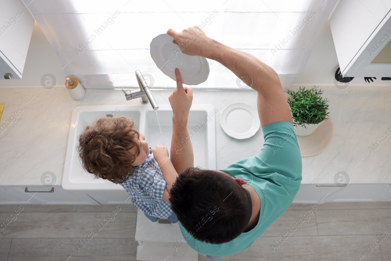 Father and his son washing dishes together in kitchen at home, top view Photo of Father and his son washing dishes together in kitchen at home, top view