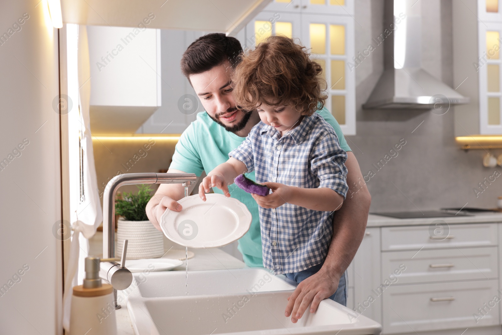 Father and his son washing dishes together in kitchen at home Photo of Father and his son washing dishes together in kitchen at home