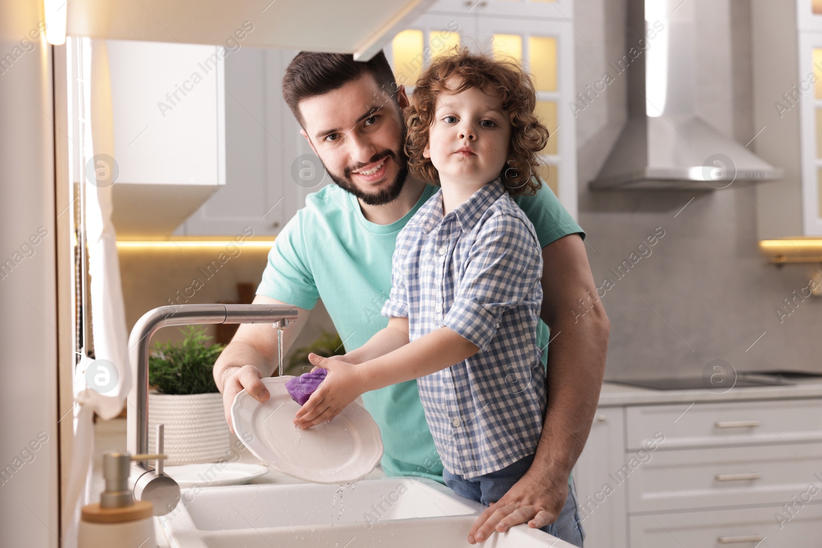 Father and his son washing dishes together in kitchen at home Photo of Father and his son washing dishes together in kitchen at home