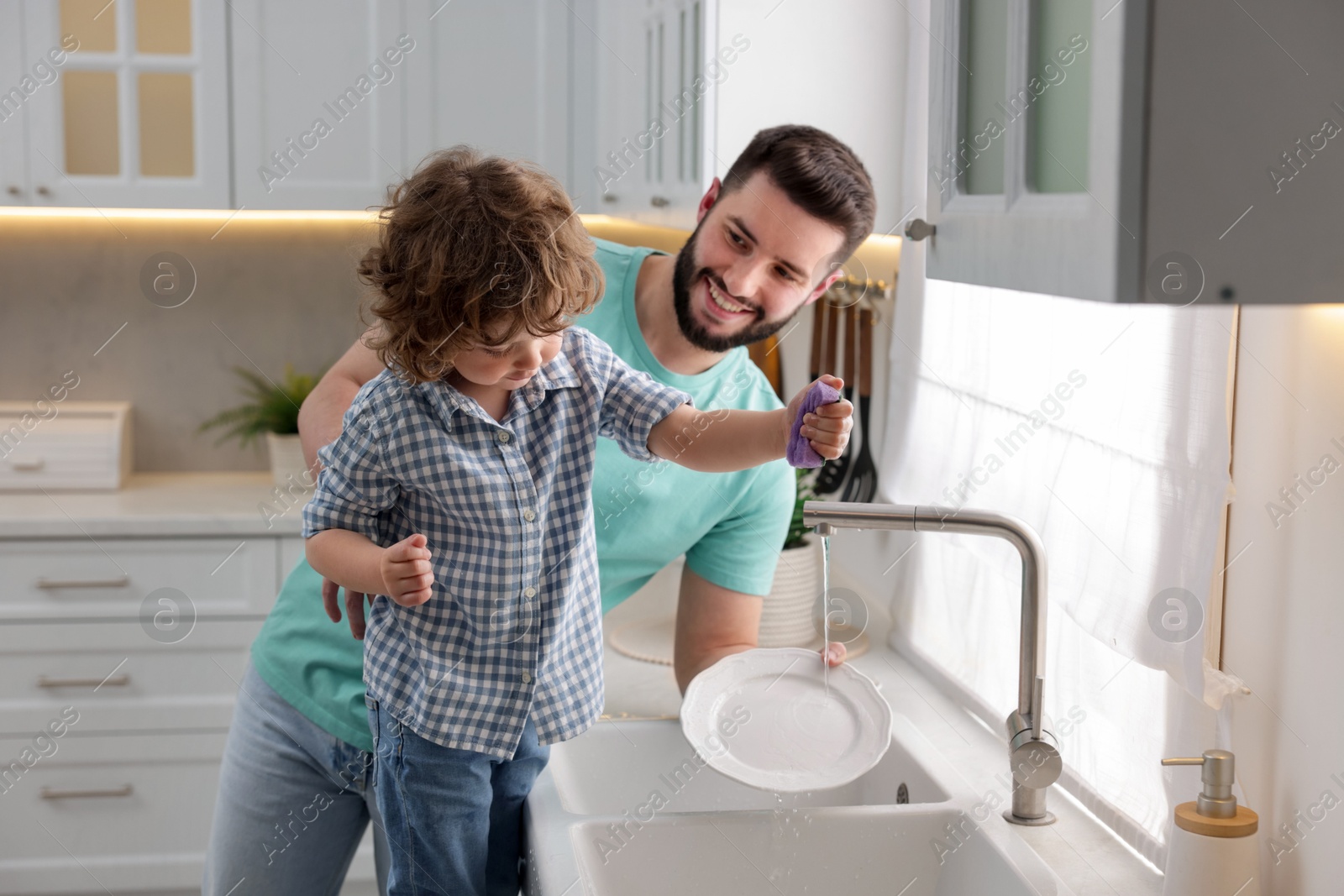 Father and his son washing dishes together in kitchen at home Photo of Father and his son washing dishes together in kitchen at home