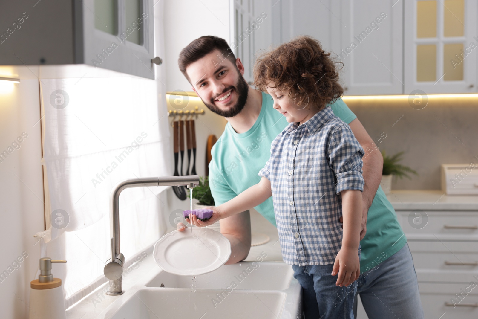 Father and his son washing dishes together in kitchen at home Photo of Father and his son washing dishes together in kitchen at home